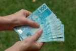 Pessoa segurando notas de cem reais — conceito de investimento em Tesouro Direto