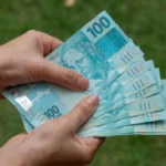 Pessoa segurando notas de cem reais — conceito de investimento em Tesouro Direto