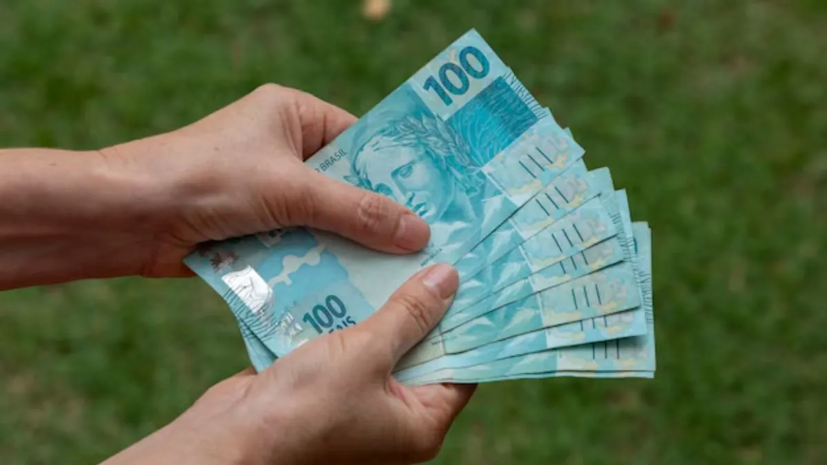 Pessoa segurando notas de cem reais — conceito de investimento em Tesouro Direto